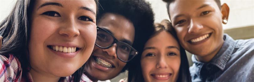 Close up picture of four teens smiling at a camera
