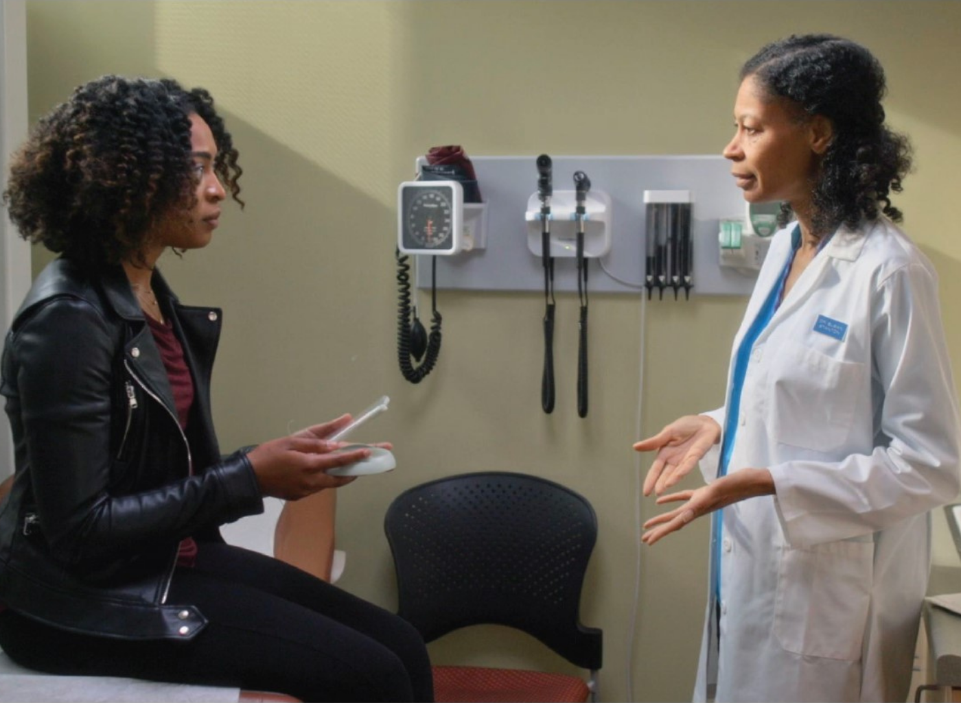 A female doctor converses with her female patient on the exam table